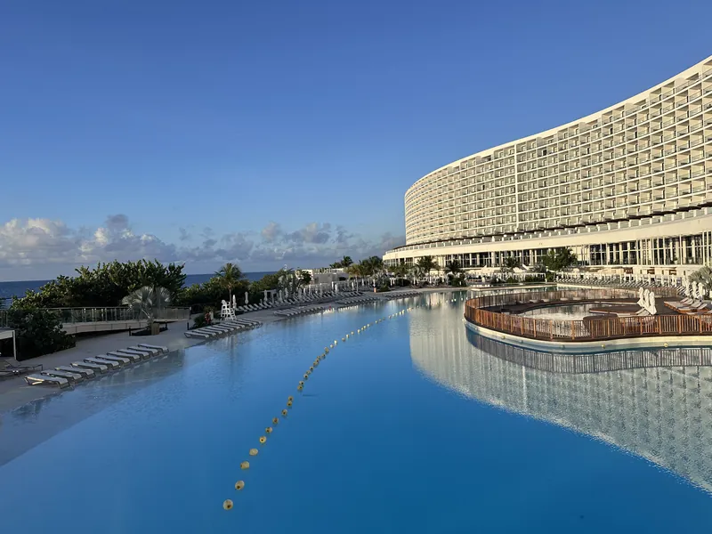 The curved hotel tower above the lagoon pool at sunrise, AVA Resort Cancún